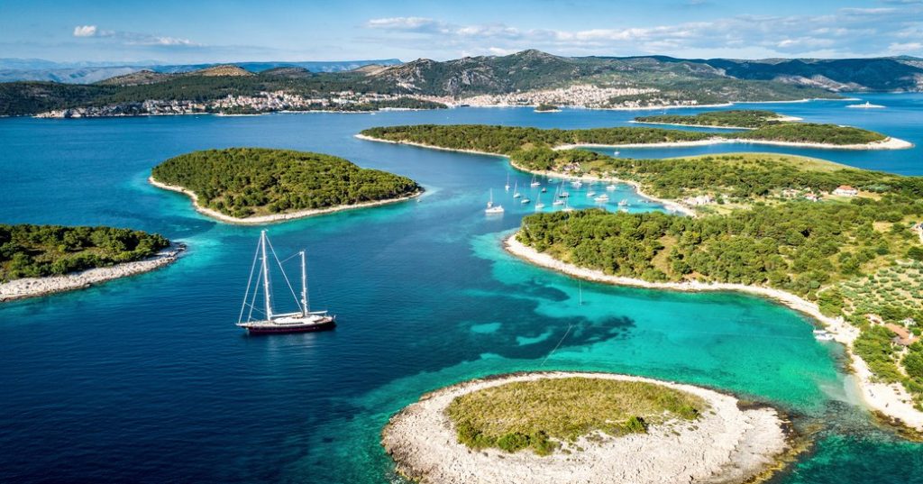 bright blue color of the Adriatic Sea off the coast of Croatia - small sailboat is seen in the foreground of the picture.